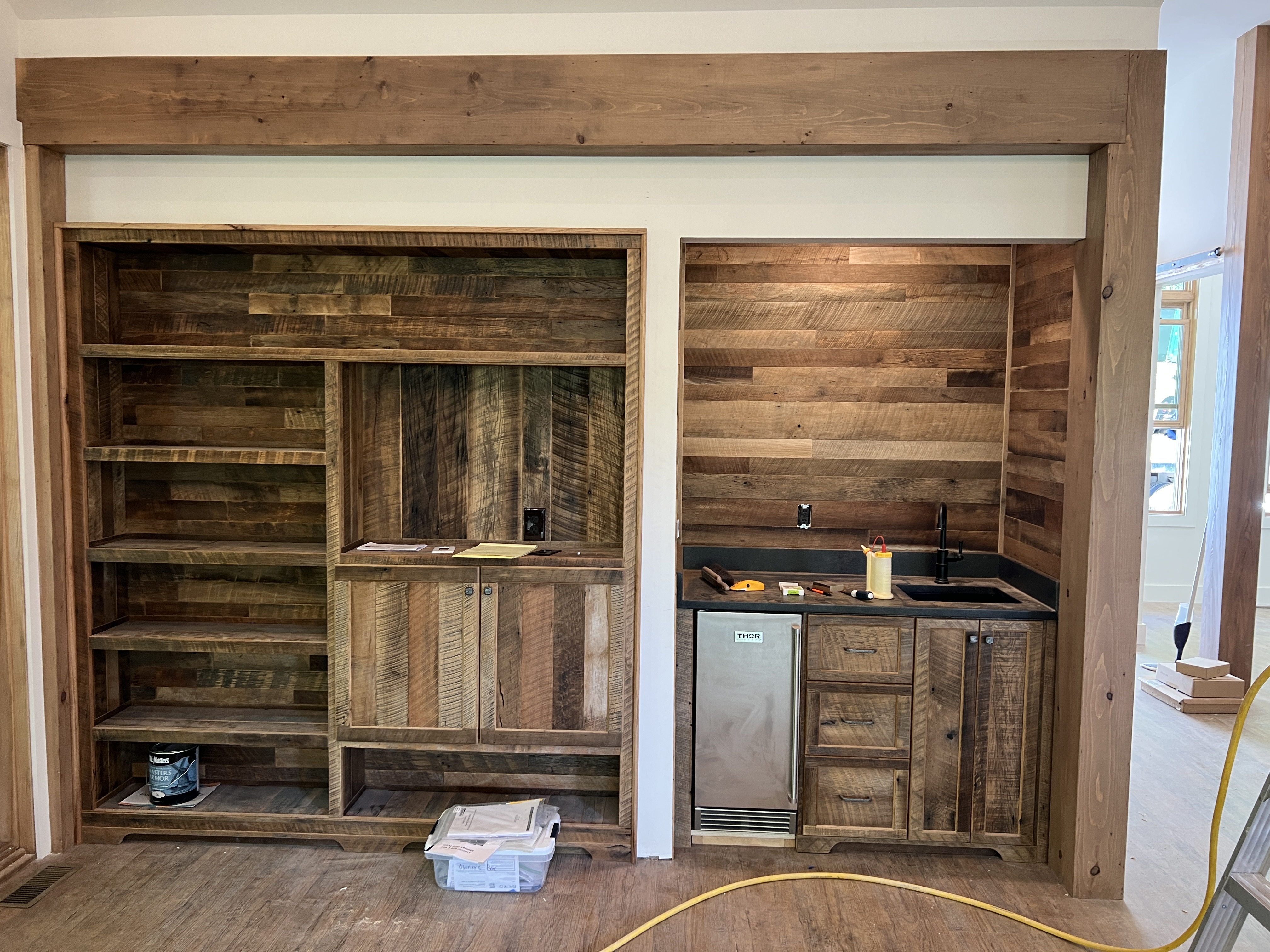 Full reclaimed wood built-in wall unit with bookshelf and wet bar