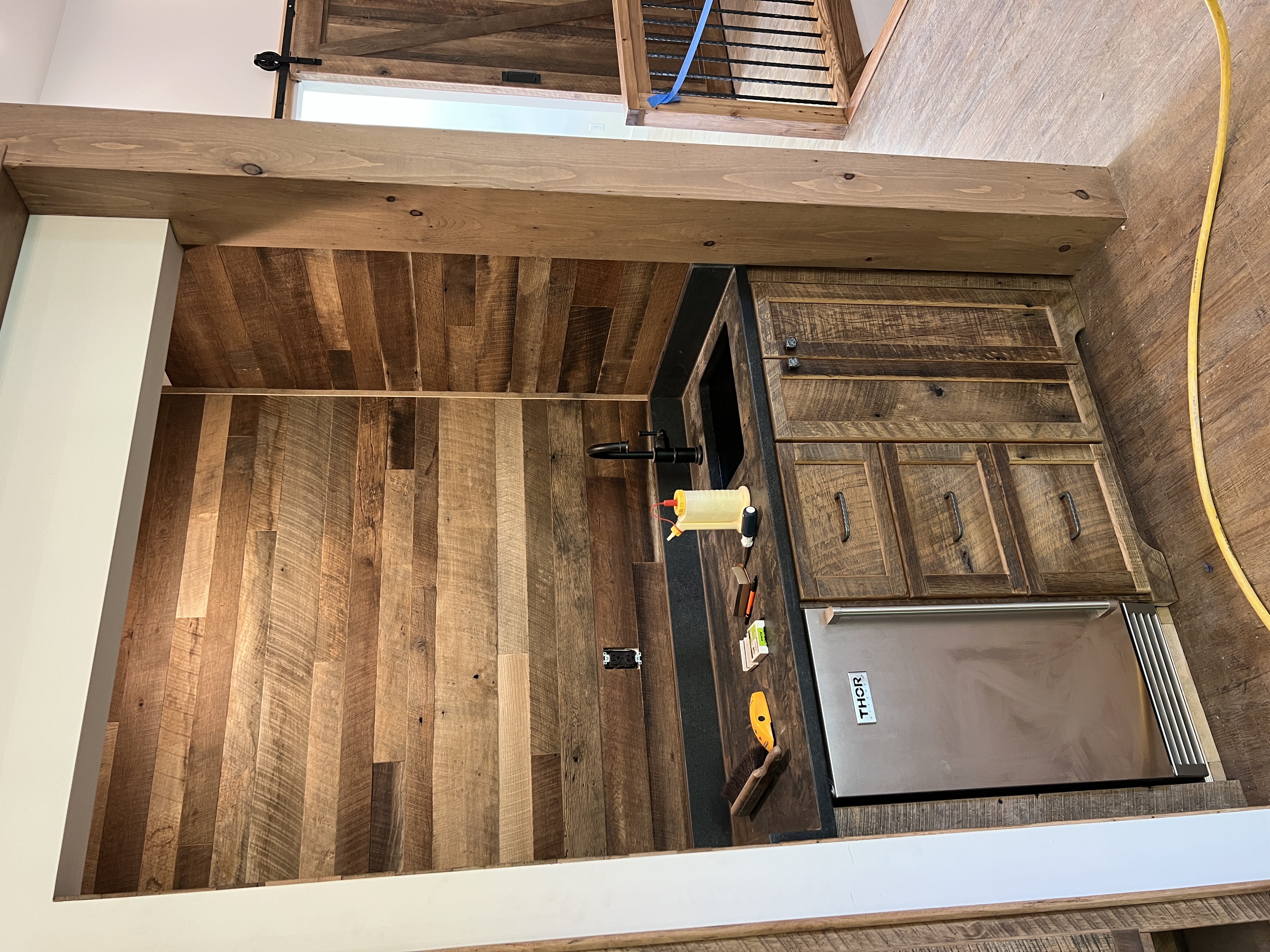Wide angle view of reclaimed wood wet bar with barn door in background